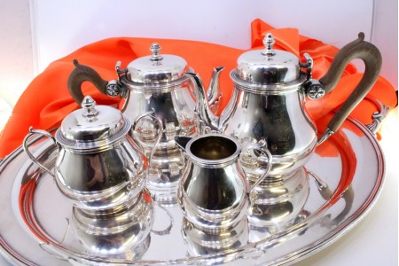 Serviço de chá e café em prata composto por chaleira, cafeteira, açucareiro e leiteira com pegas em madeira de castanho, bandeja relevada nas asas e recortes.